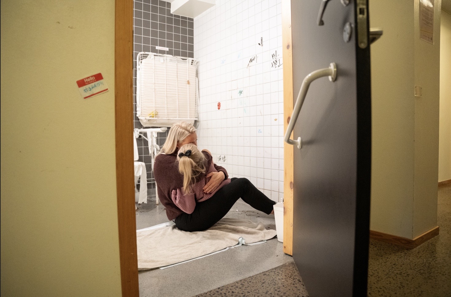 En vuxen kvinna kramar ett barn på golvet på en offentlig toalett